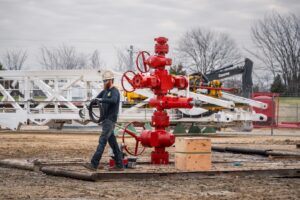 Image of a wellhead installed with a worker doing maintenance on the wellhead. This Stream-Flo wellhead is painted red.